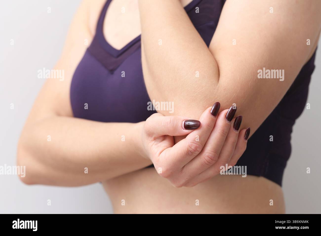 Ellenbogengelenk-Schmerzsymptom. Frau, die einen schmerzenden Arm hält. Entzündungs- oder Verletzungskonzept. Muskel- oder Sehnenbelastung. Zur medizinischen Frage der oberen Extremität. Stockfoto