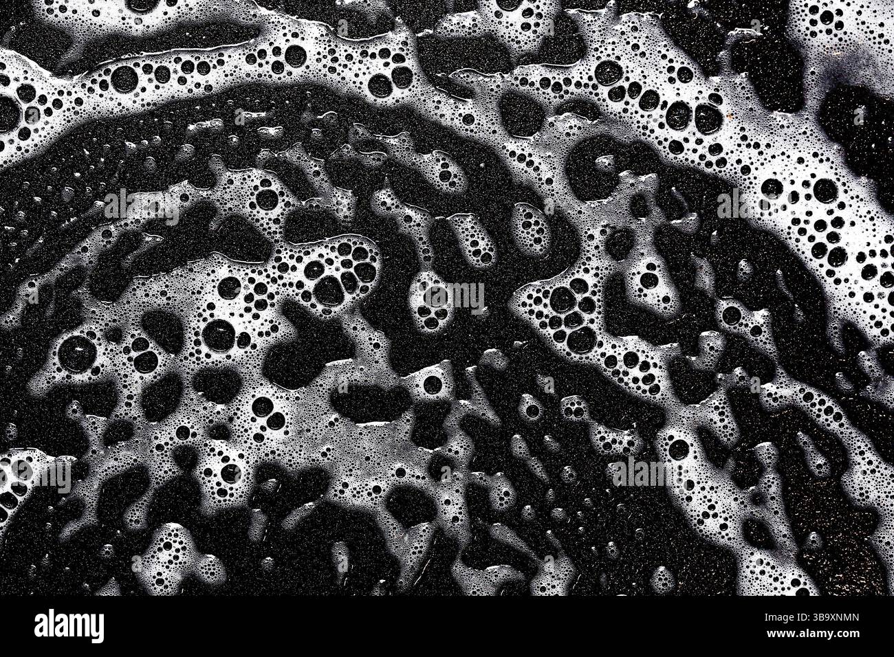 Schwarz-weiße Seifenblasen. Abstrakte Schaumblätter. Textur-Makro für Nassreinigung. Monochromes Muster der Waschflüssigkeit. Waschmittel im Badezimmer. Stockfoto