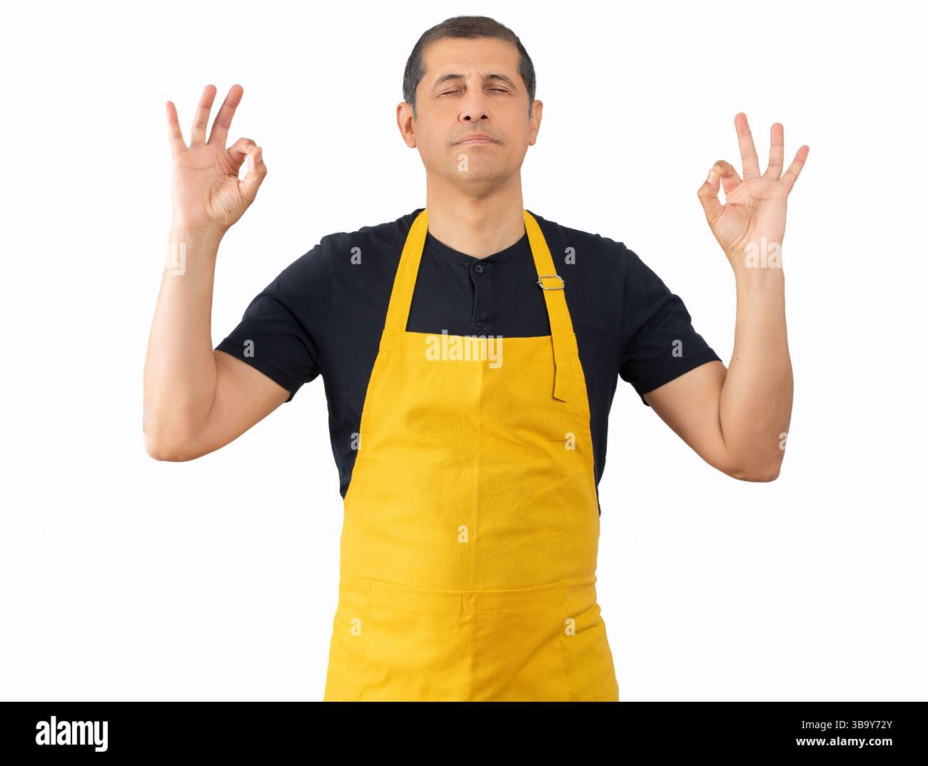 Mann, der gelbe Schürze des Mitarbeiters über isoliertem weißem Hintergrund trägt, entspannen und lächeln mit geschlossenen Augen, indem er Meditationsgeste mit Fingern macht. Yoga-Konzept Stockfoto