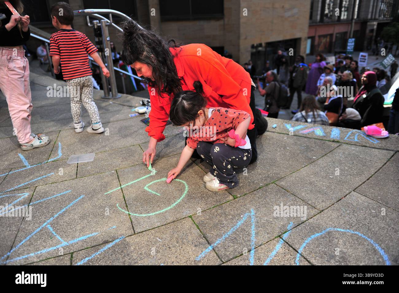 Glasgow, Großbritannien. 11. Mai 2025 - Mutter und Tochter werden während des Protestes auf dem Boden schreiben gesehen. Demonstranten versammelten sich vor den Stufen der Buchannan Street, um gegen die israelische Besetzung Palästinas und den vom Westen unterstützten Völkermord an den Palästinensern zu protestieren. Quelle: Eastern Goodwin Media/Alamy Live News Stockfoto