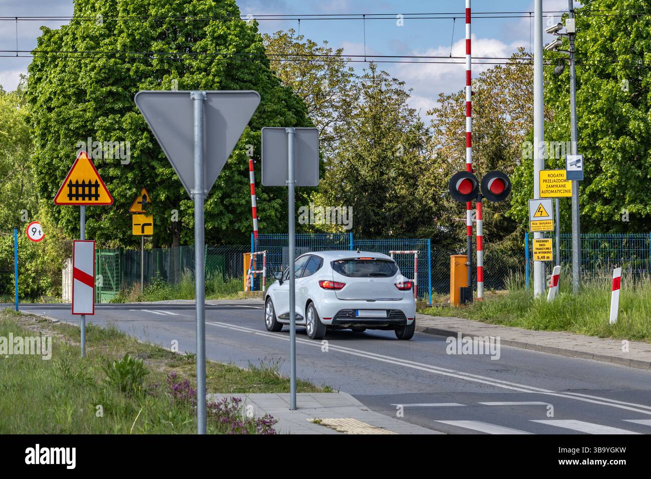 Autos passieren einen Bahnübergang mit roter Ampel, beschädigte Bahnbarrieren am Übergang, Verkehrsverletzung Stockfoto