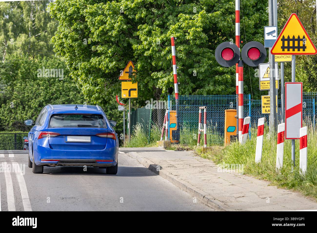 Autos passieren einen Bahnübergang mit roter Ampel, beschädigte Bahnbarrieren am Übergang, Verkehrsverletzung Stockfoto