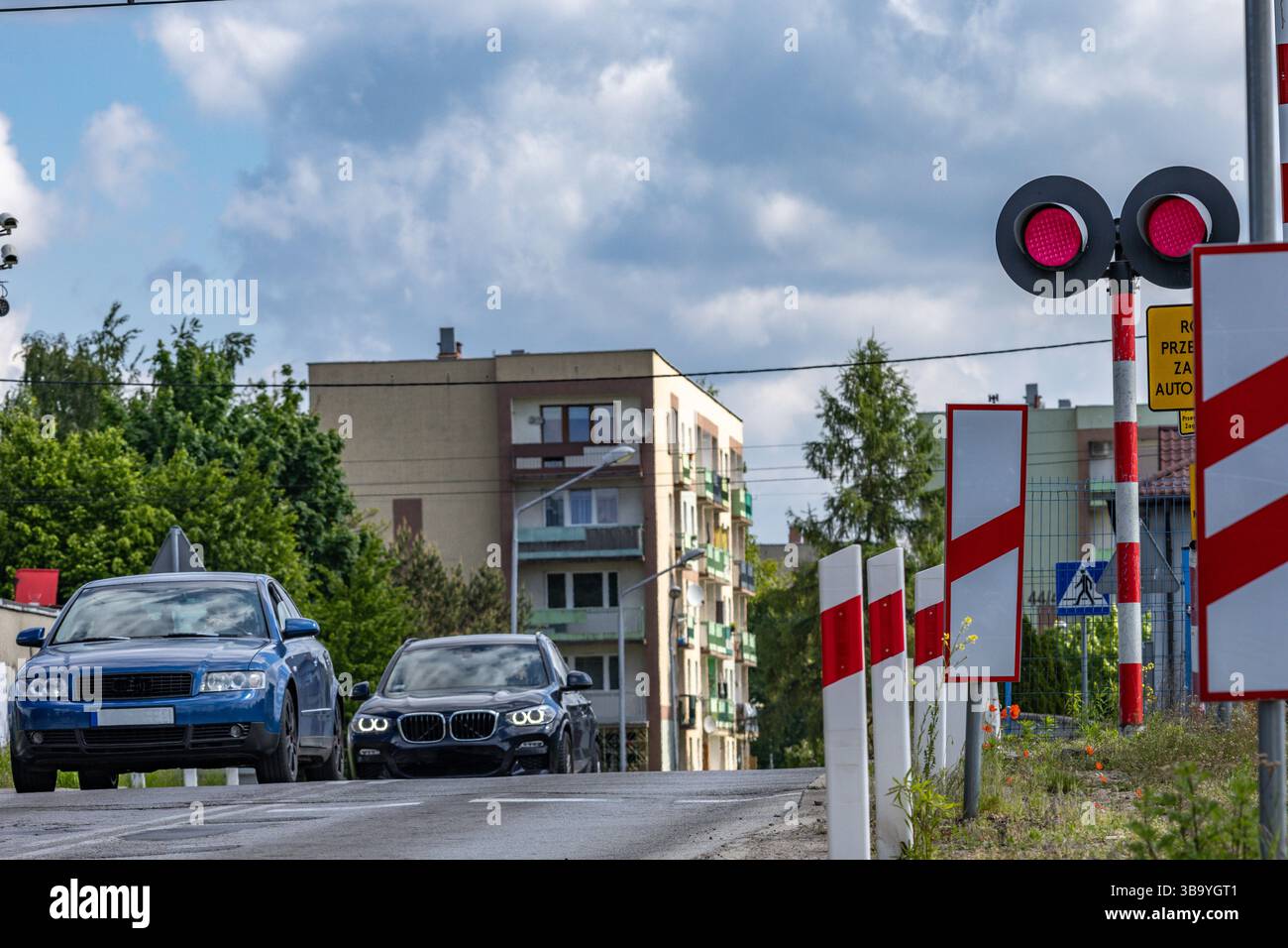 Autos passieren einen Bahnübergang mit roter Ampel, beschädigte Bahnbarrieren am Übergang, Verkehrsverletzung Stockfoto