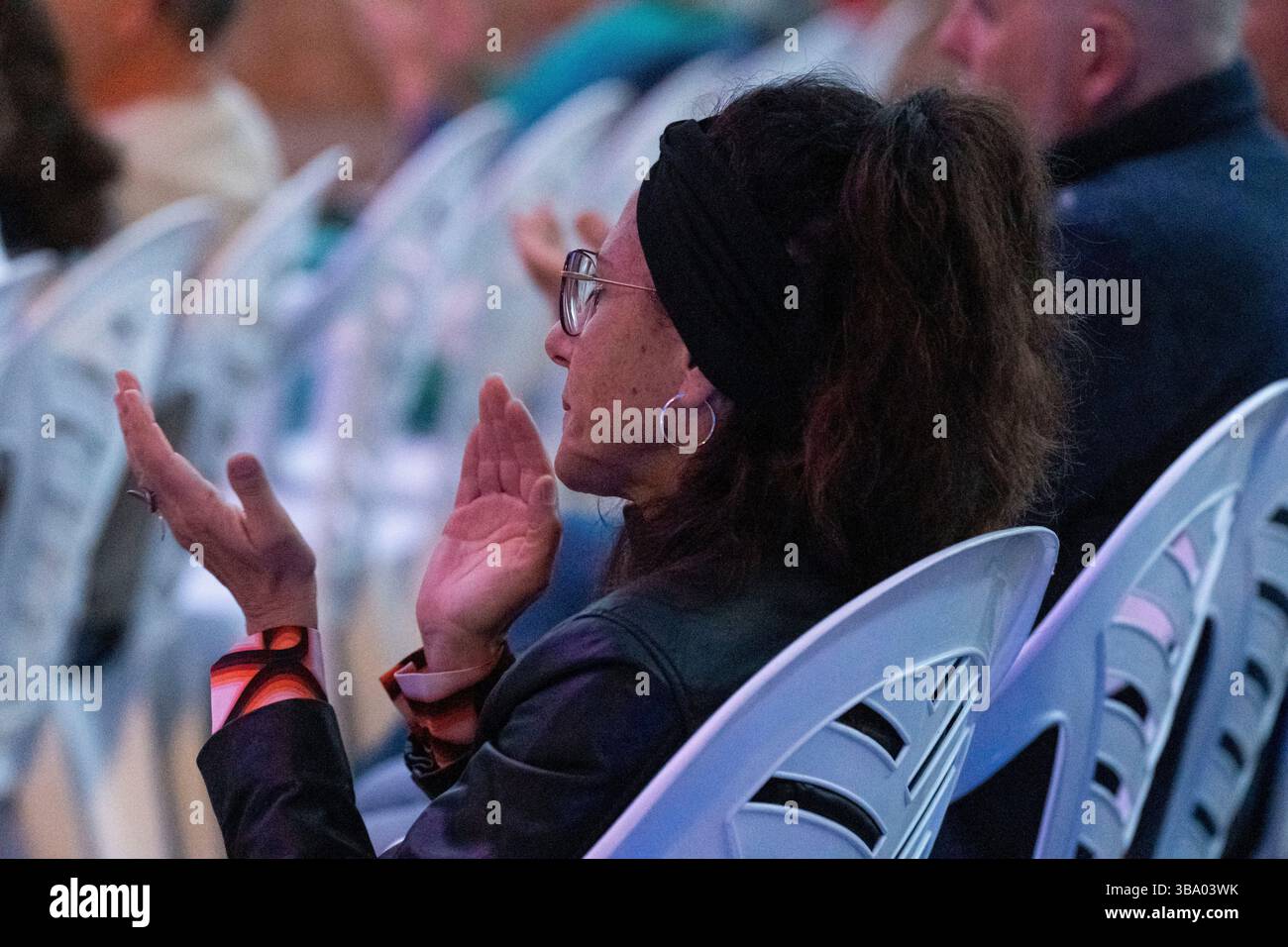 Frau in einer Reihe von Sitzen applaudiert, Konzertverse und Musik, 'Nuredduna' von Miquel Costa i Llobera, 'La deixa del geni grec', Coves d'Artà, Mallorca, Balearen, Spanien. Stockfoto
