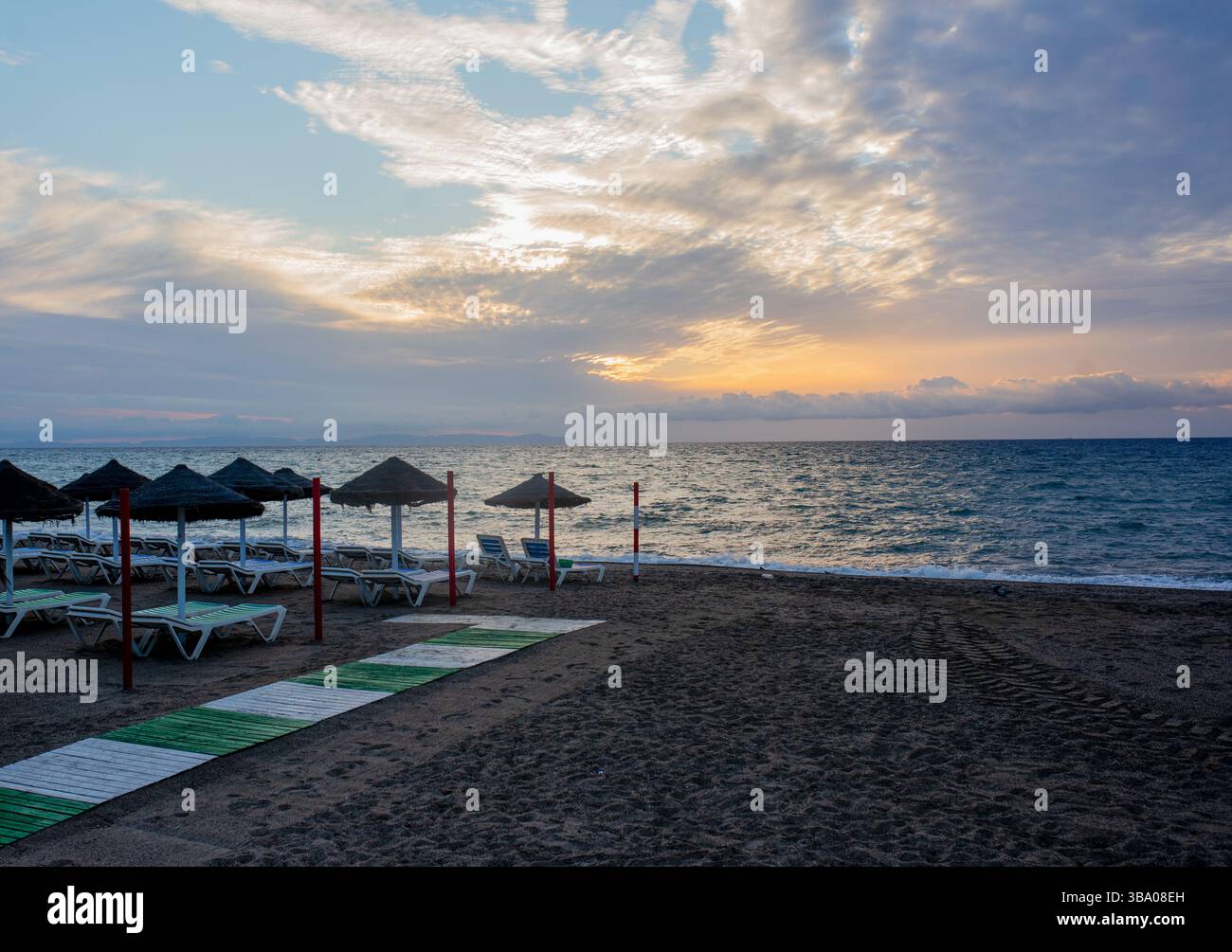 Weiße, weiche Sonnenliegen am Ufer eines Sandstrands. Tropisches Resort, Morgensonne, weiße Wolken am blauen Himmel, Blick auf das Meer, die Berge und Stockfoto