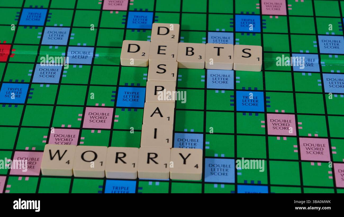 Das Konzept von Geldsorgen und finanziellen Schwierigkeiten wird auf einem Scrabble-Brett mit den Worten Geld, Schulden, Verzweiflung, Sorge, Stress formuliert. Stockfoto