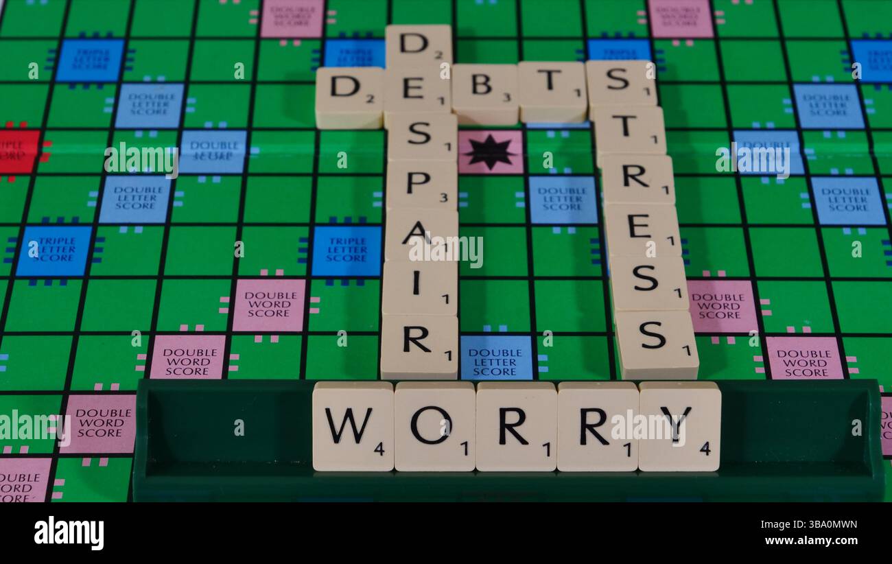 Das Konzept von Geldsorgen und finanziellen Schwierigkeiten wird auf einem Scrabble-Brett mit den Worten Geld, Schulden, Verzweiflung, Sorge, Stress formuliert. Stockfoto