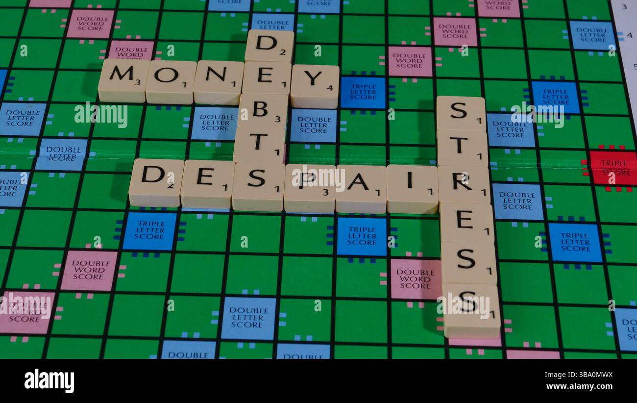 Das Konzept von Geldsorgen und finanziellen Schwierigkeiten wird auf einem Scrabble-Brett mit den Worten Geld, Schulden, Verzweiflung, Sorge, Stress formuliert. Stockfoto