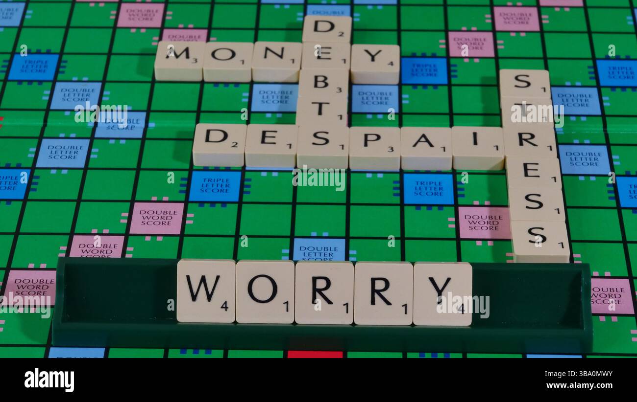 Das Konzept von Geldsorgen und finanziellen Schwierigkeiten wird auf einem Scrabble-Brett mit den Worten Geld, Schulden, Verzweiflung, Sorge, Stress formuliert. Stockfoto