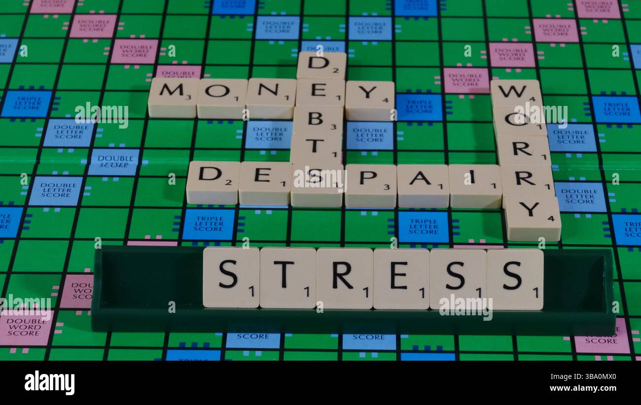 Das Konzept von Geldsorgen und finanziellen Schwierigkeiten wird auf einem Scrabble-Brett mit den Worten Geld, Schulden, Verzweiflung, Sorge, Stress formuliert. Stockfoto