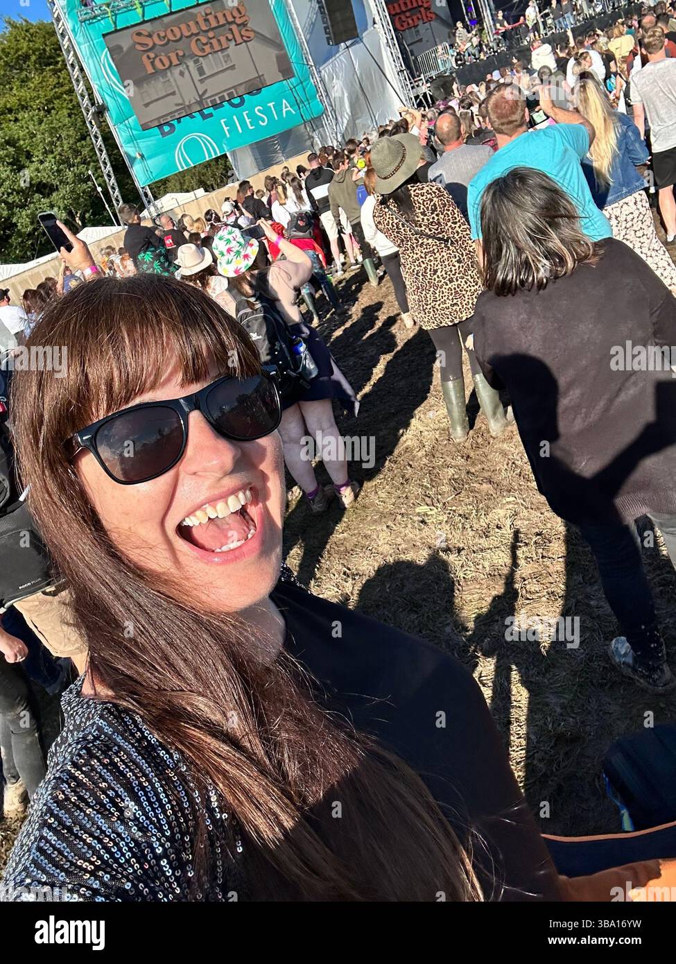 Festivalbesucher in einem Pailletten-Schal, der am 6. August 2023 die Cheshire Balloon Fiesta im Bolesworth Estate, Tattenhall, Großbritannien, genießt. Nur redaktionelle Verwendung. - Smartphone-aufgenommenes Stockfoto