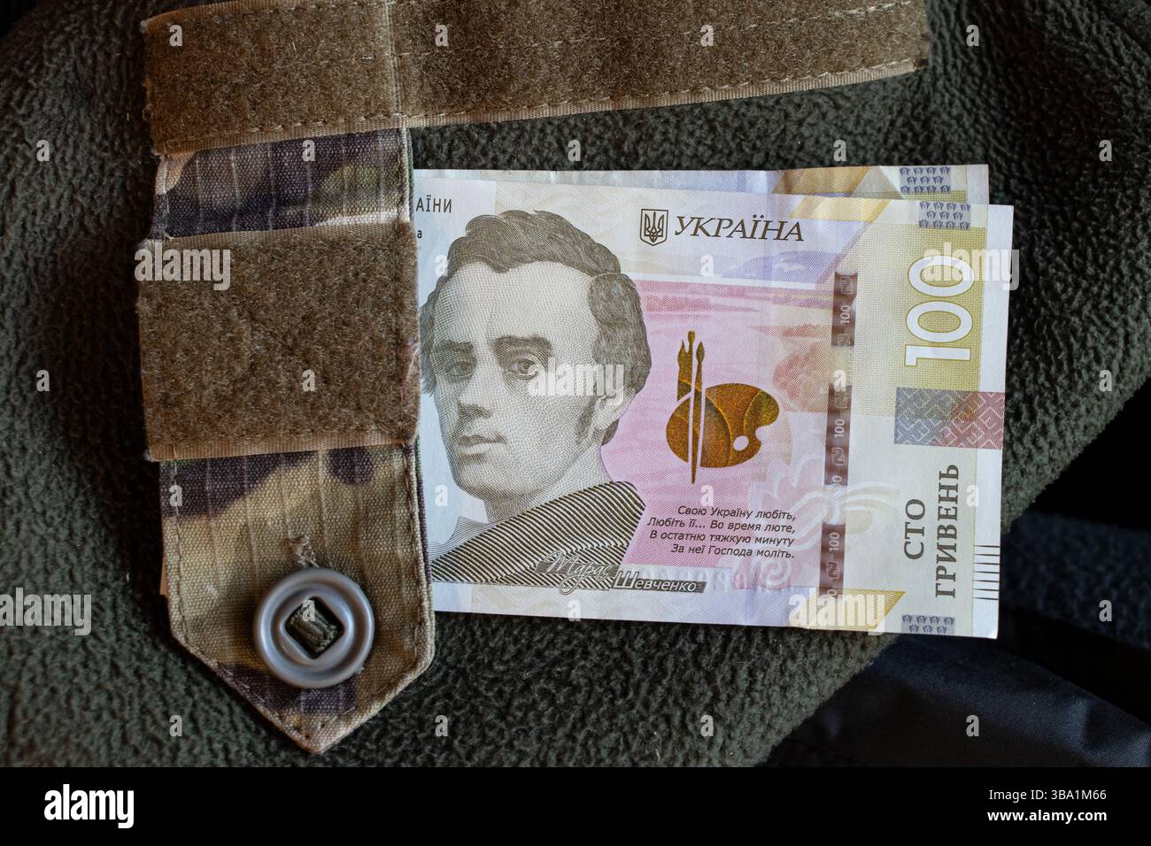 100 Griwna auf der Militäruniform des ukrainischen Soldaten, Finanzierung der ukrainischen Armee Stockfoto