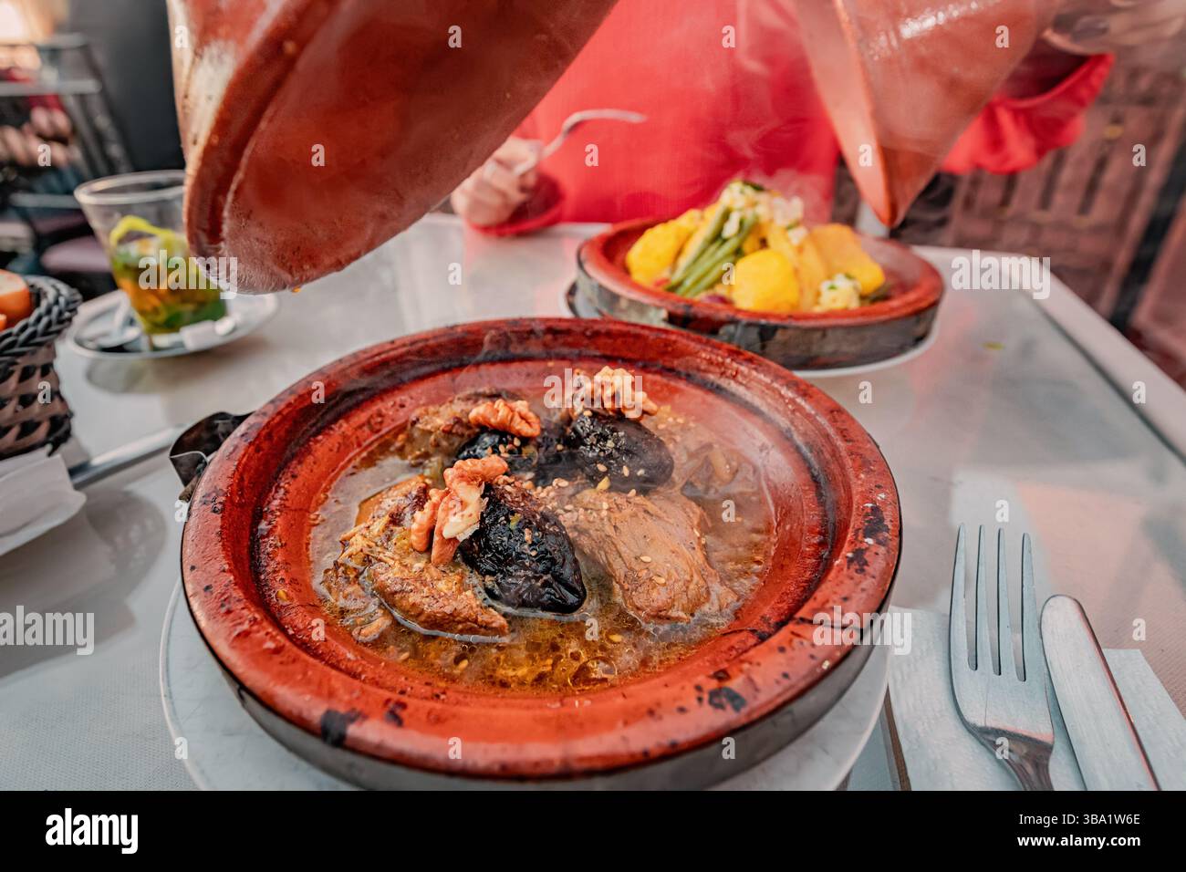 Dampfende Tajine mit Lammpflaumen, Walnüssen und Gewürzen, die in einem traditionellen Terrakotta-Gericht in Marokko serviert werden Stockfoto