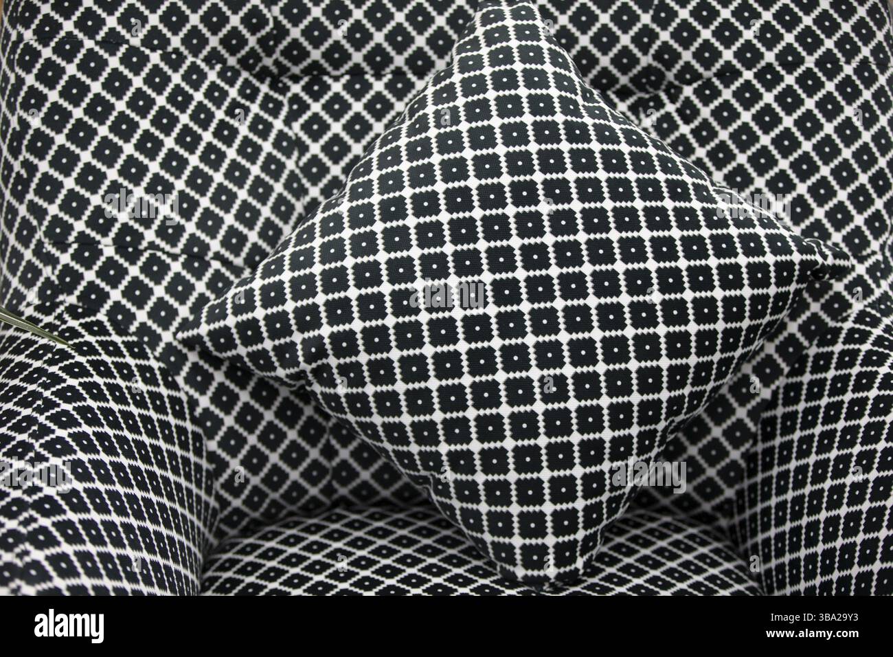 Geometrisches Muster mit schwarz-weißen Rauten auf Kissen und Stuhl Stockfoto
