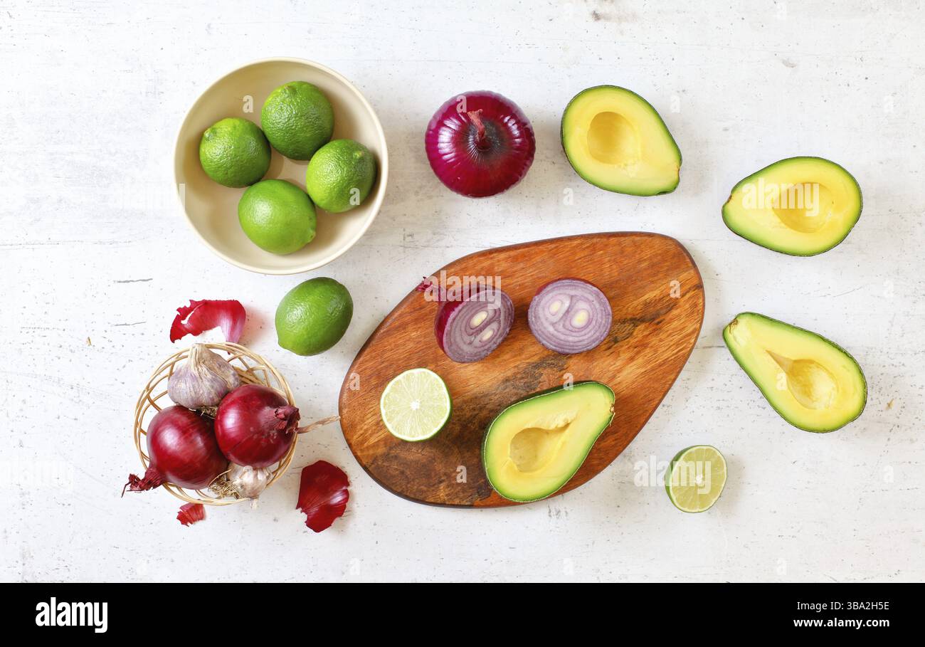 Avocadohälften, Limetten und Zwiebeln - grundlegende Guacamole-Zutaten auf weißem Arbeitsbrett, Flachbild-Foto, Liptovsky Hradok, Slowakei, Europa Stockfoto
