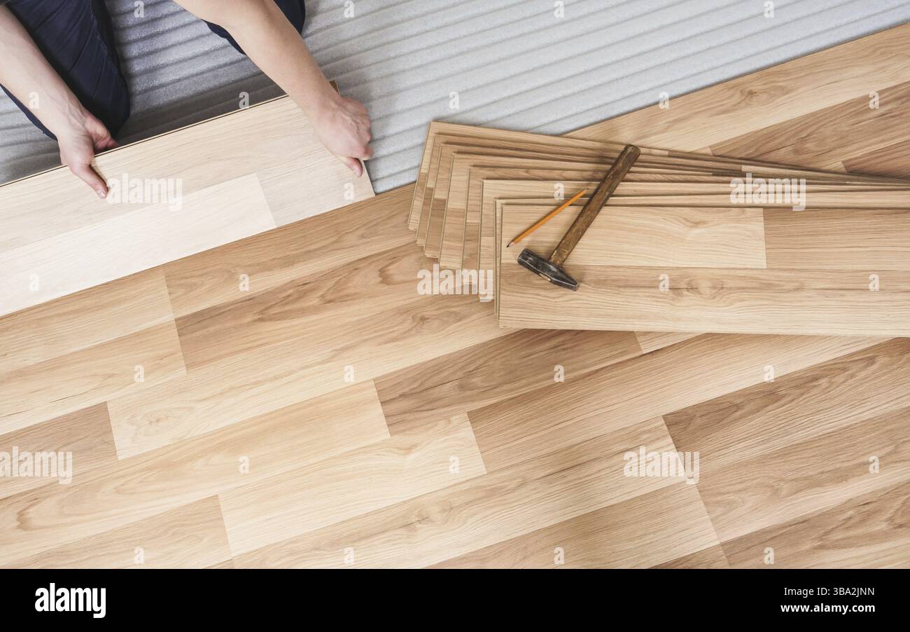 Installation von Laminatboden, Detail auf den Händen des Mannes mit Holzfliesen, über weißer Schaumstoffunterlage, Liptovsky Mikulas, Slowakei, Europa Stockfoto
