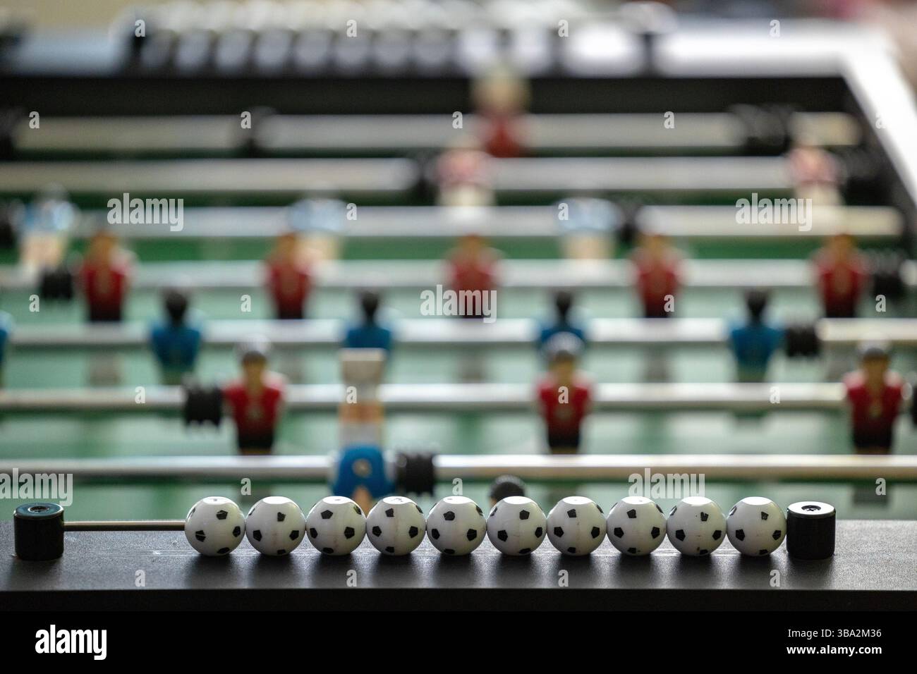 Ein Tischkicker mit roten und blauen Spielfiguren, die auf Metallstangen montiert sind. Im Vordergrund stehen neun Kicker-Punktmarker, die für die Verfolgung verwendet werden Stockfoto