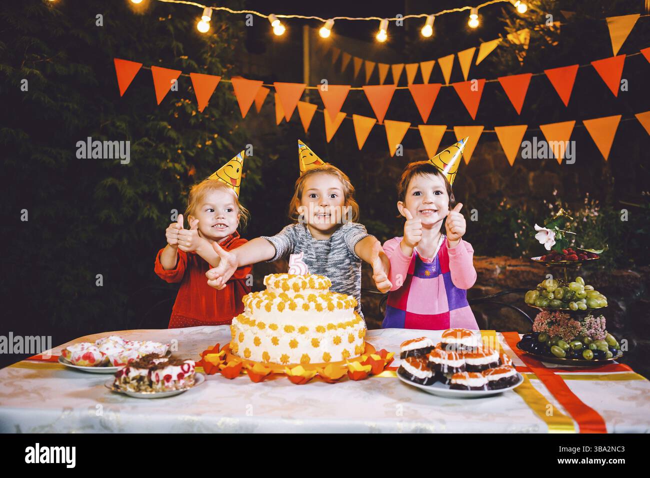 Kindergeburtstage. Drei fröhliche Kinder Mädchen Kuchen essen, mit ihren Händen und Verschmieren ihr Gesicht. Spaß und festliche Stimmung in der Dekorierten c Stockfoto
