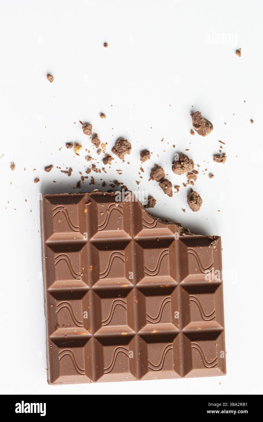 Defektes Stück Schokolade mit Krümel auf einem weißen Hintergrund. Kakao Dessert Stockfoto