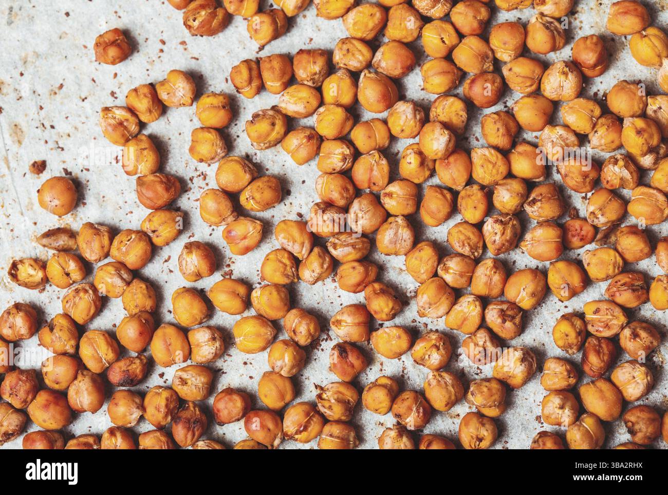 Scharfe gebackene Kichererbsen auf Backpapier verstreut Stockfoto