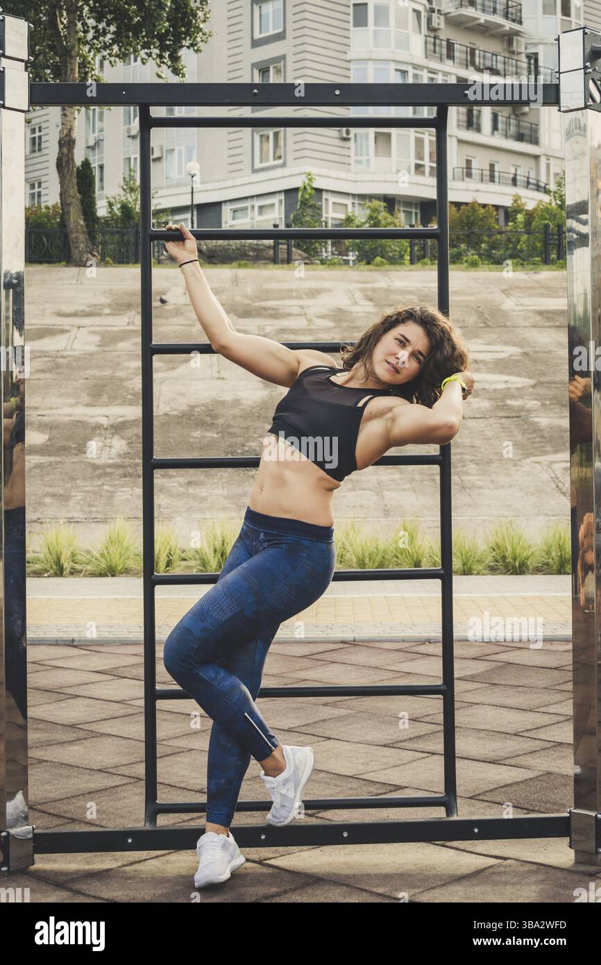 Attraktive passen junge Frau im Sport tragen Rest auf der Straße trainieren. Die gesunden Lebensstil in der Stadt. Street Portrait starke Frau posiert im Fitnessstudio Stockfoto