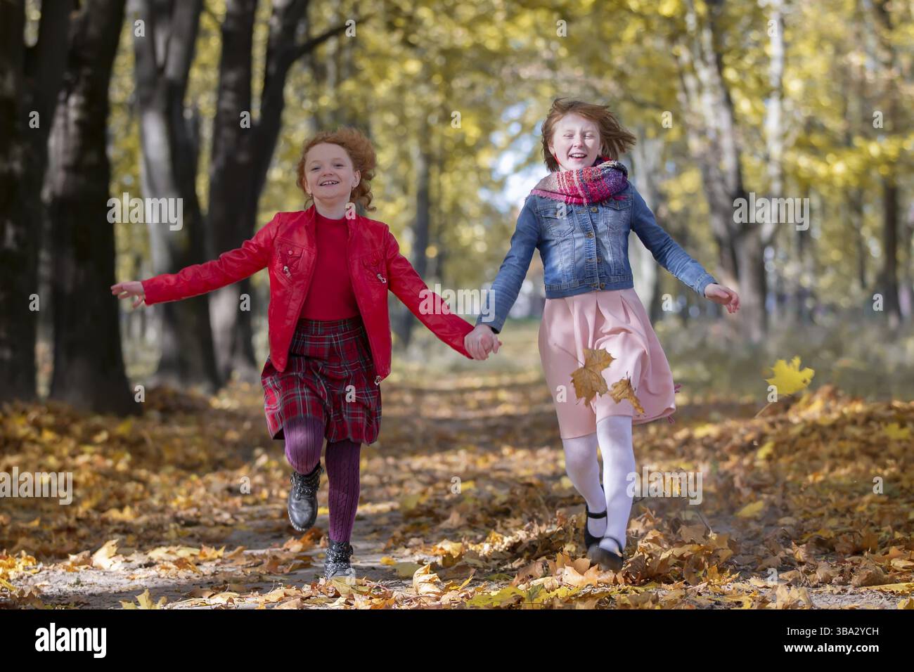 Fröhliche Kinder spielen im Herbstpark an einem warmen sonnigen Herbsttag Stockfoto