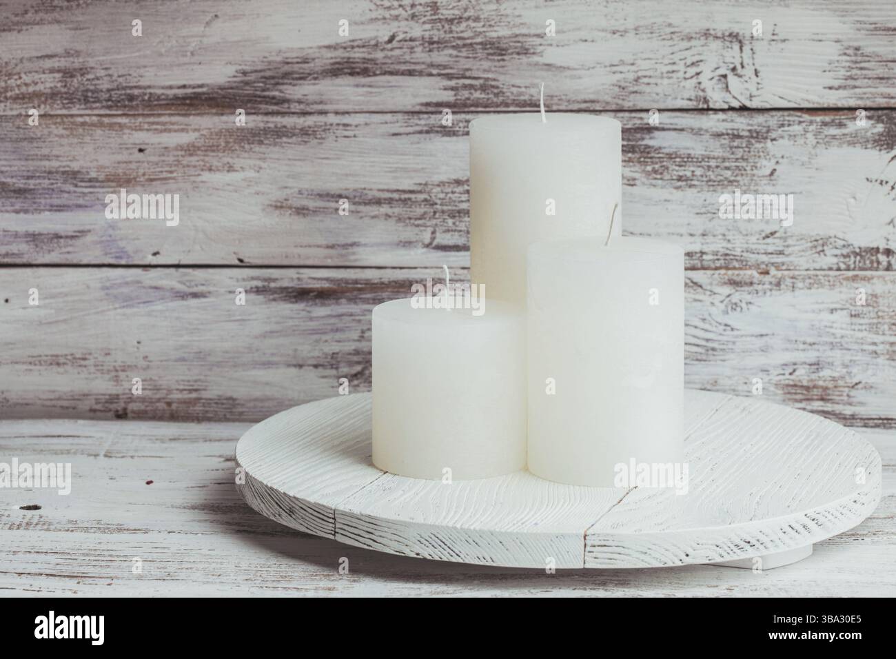 Drei weiße Weihnachtskerzen auf einem runden Standfuß Stockfoto