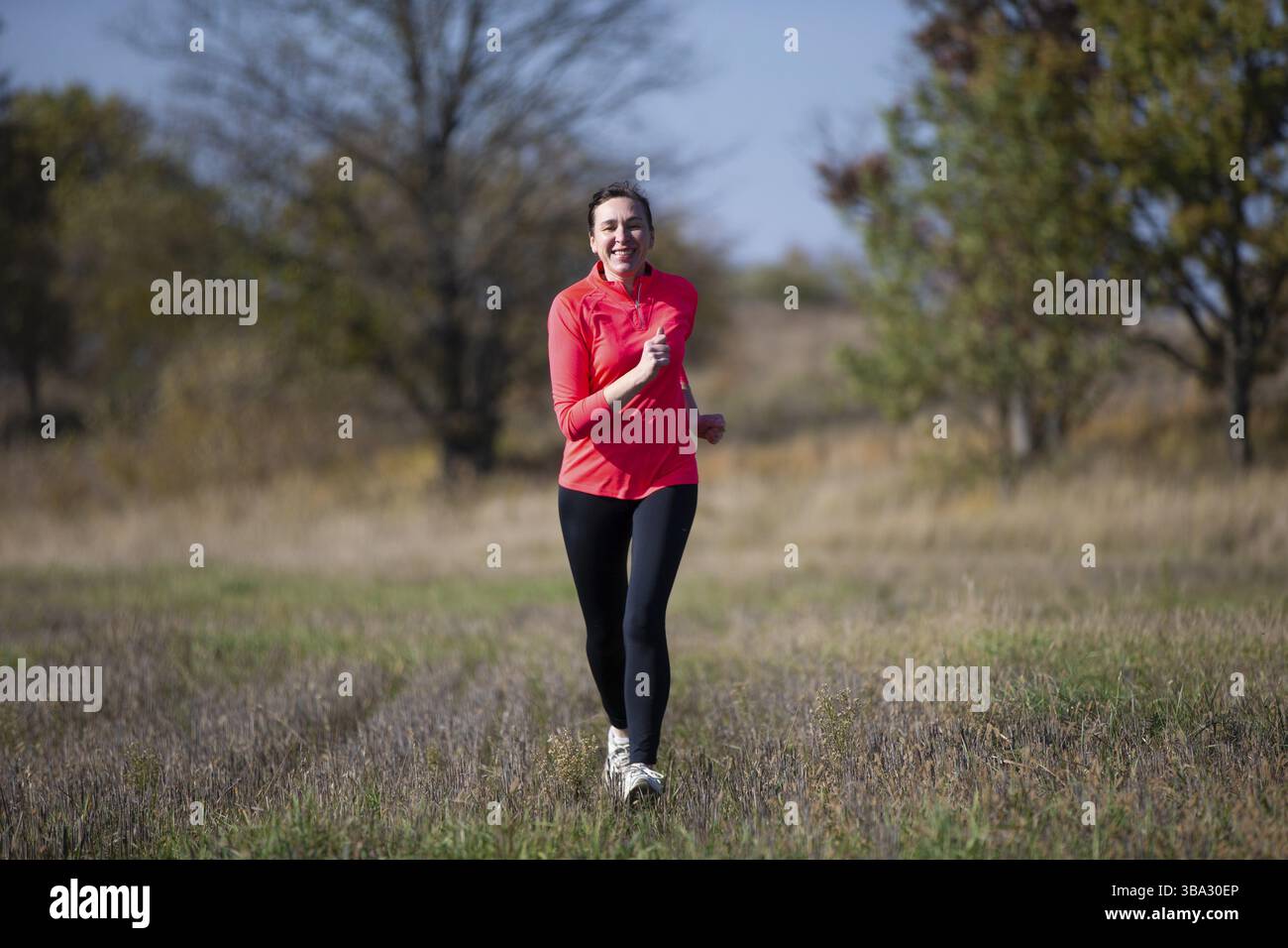 Fröhliche sportliche ältere Frau. Positive ältere Frau macht einen Jogg. Porträt einer sportlichen älteren Frau im Park Stockfoto