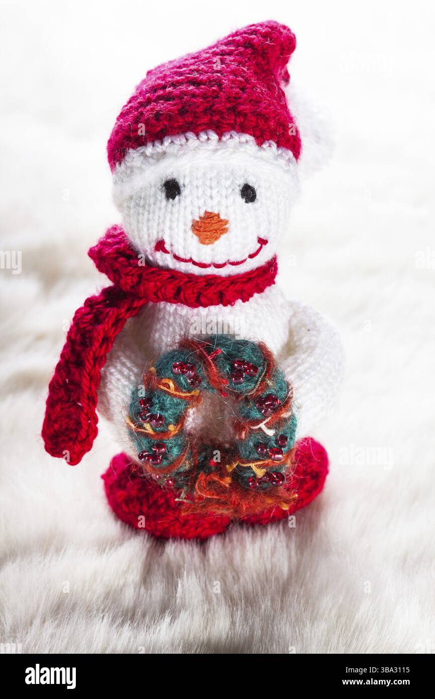Gestrickte Schneemann mit Adventskranz auf weißen Schnee Stockfoto