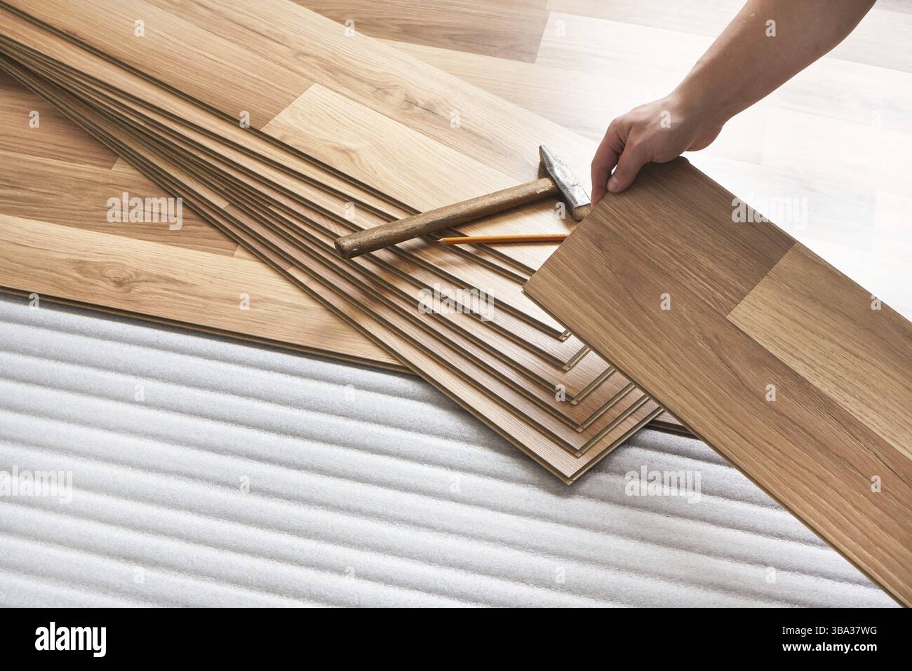 Installation von Laminatboden, Detail auf den Händen des Mannes mit Holzfliesen, über weißer Schaumstoffunterlage, Liptovsky Mikulas, Slowakei, Europa Stockfoto