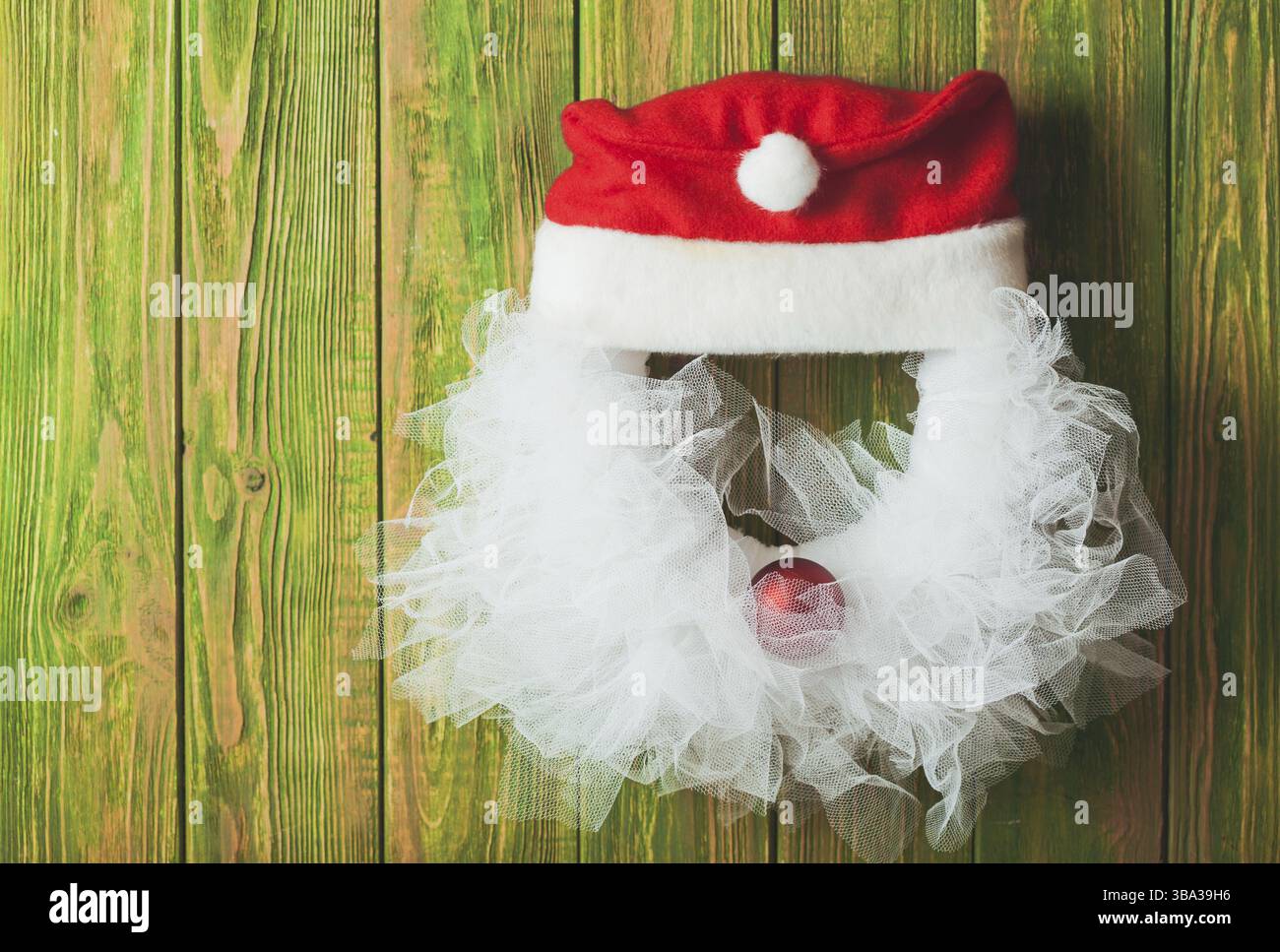 Weihnachtskranz wie der Weihnachtsmann aus Spitze und roter Kugel an der Holztür Stockfoto