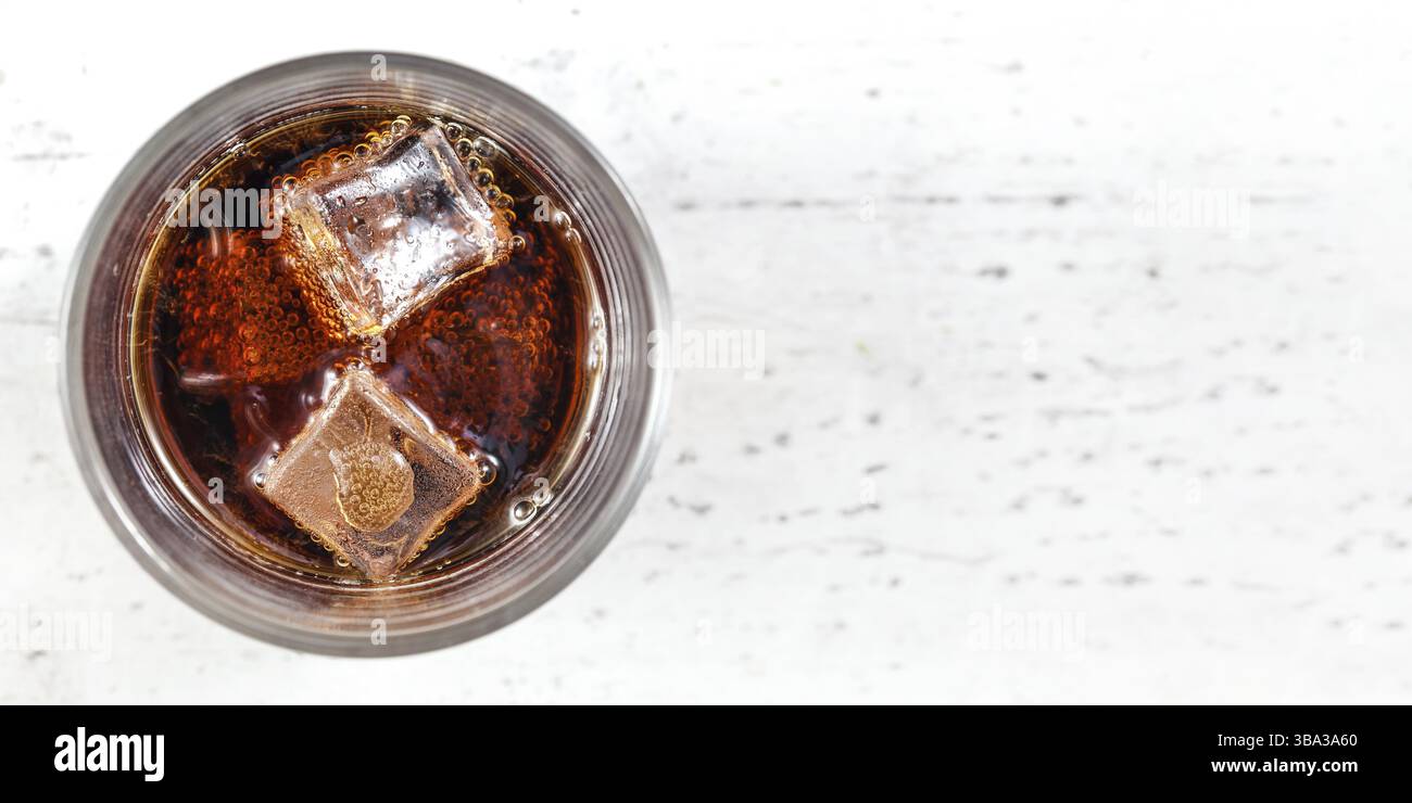 Blick auf die Tischplatte, Glas mit Cola-Getränk und Eiswürfeln auf Weißtafel. Großes Foto, Platz für Text rechts, Liptovsky Hradok, Slowakei, Europa Stockfoto