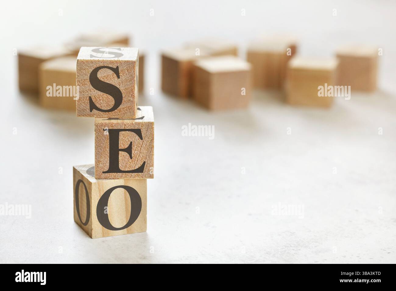Drei Holzwürfel mit den Buchstaben SEO (bedeutet Search Engine Optimization), auf weißem Tisch, mehr im Hintergrund, Platz für Text in der rechten unteren Ecke, Lipto Stockfoto