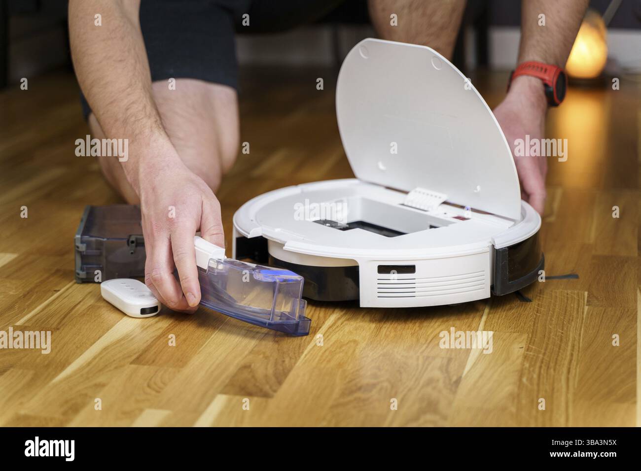 Reparatur des Roboter-Staubsaugers. Mann Befestigung Roboter Staubsauger DIY zu Hause auf dem Boden. Wartung und Service des Roboter-Staubsaugers. Smart-Gerät für Stockfoto