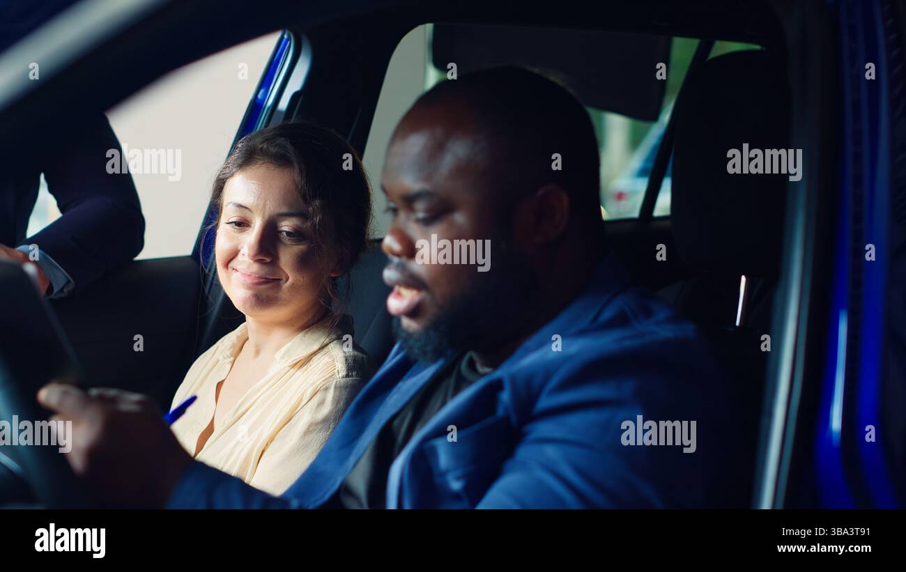 Kunden, die sich im Ausstellungsraum befinden, füllen das Feedback-Formular aus, nachdem sie die Probefahrt beendet haben und sich für den Kauf entschieden haben, zufrieden mit der Hilfe des Verkäufers. Ein Paar kauft ein Auto, nachdem es damit zufrieden war, Kamera A Stockfoto