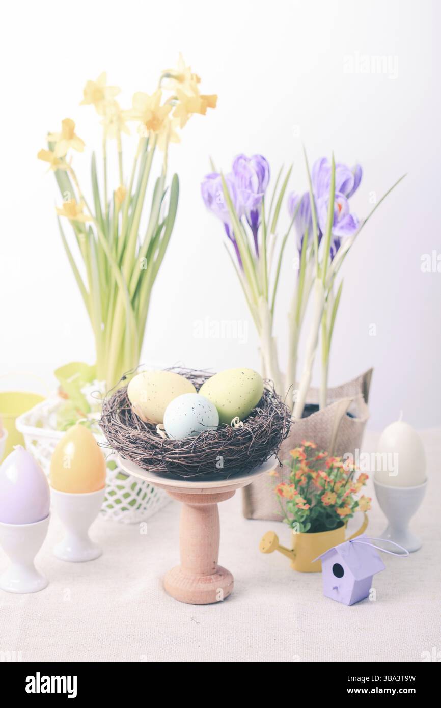 Osterdekorationen - Eierkerzen, Nest und Blumen auf dem Tisch Stockfoto