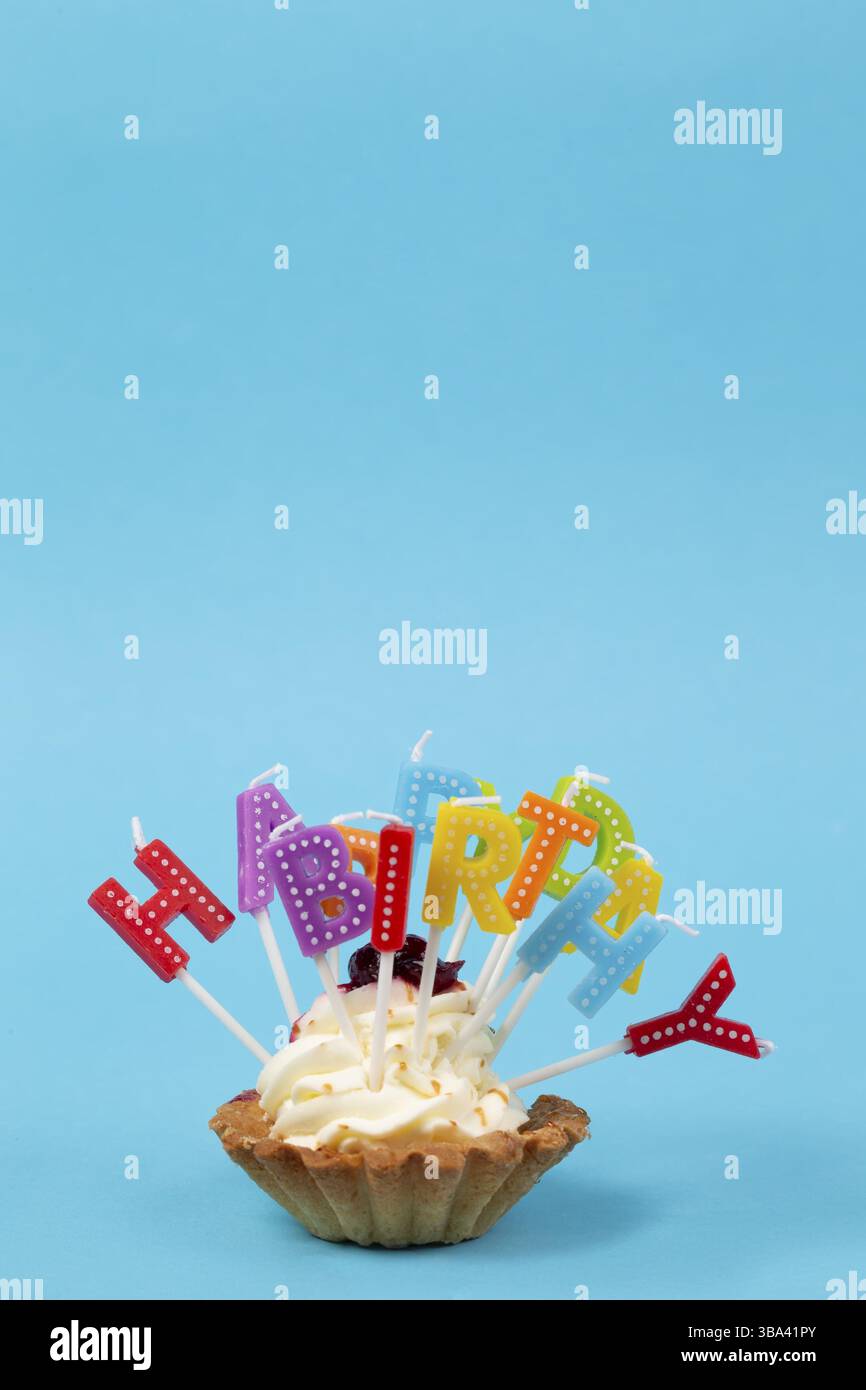 Cupcake mit regenbogenfarbenen Kerzen zum Geburtstag mit der Inschrift Stockfoto