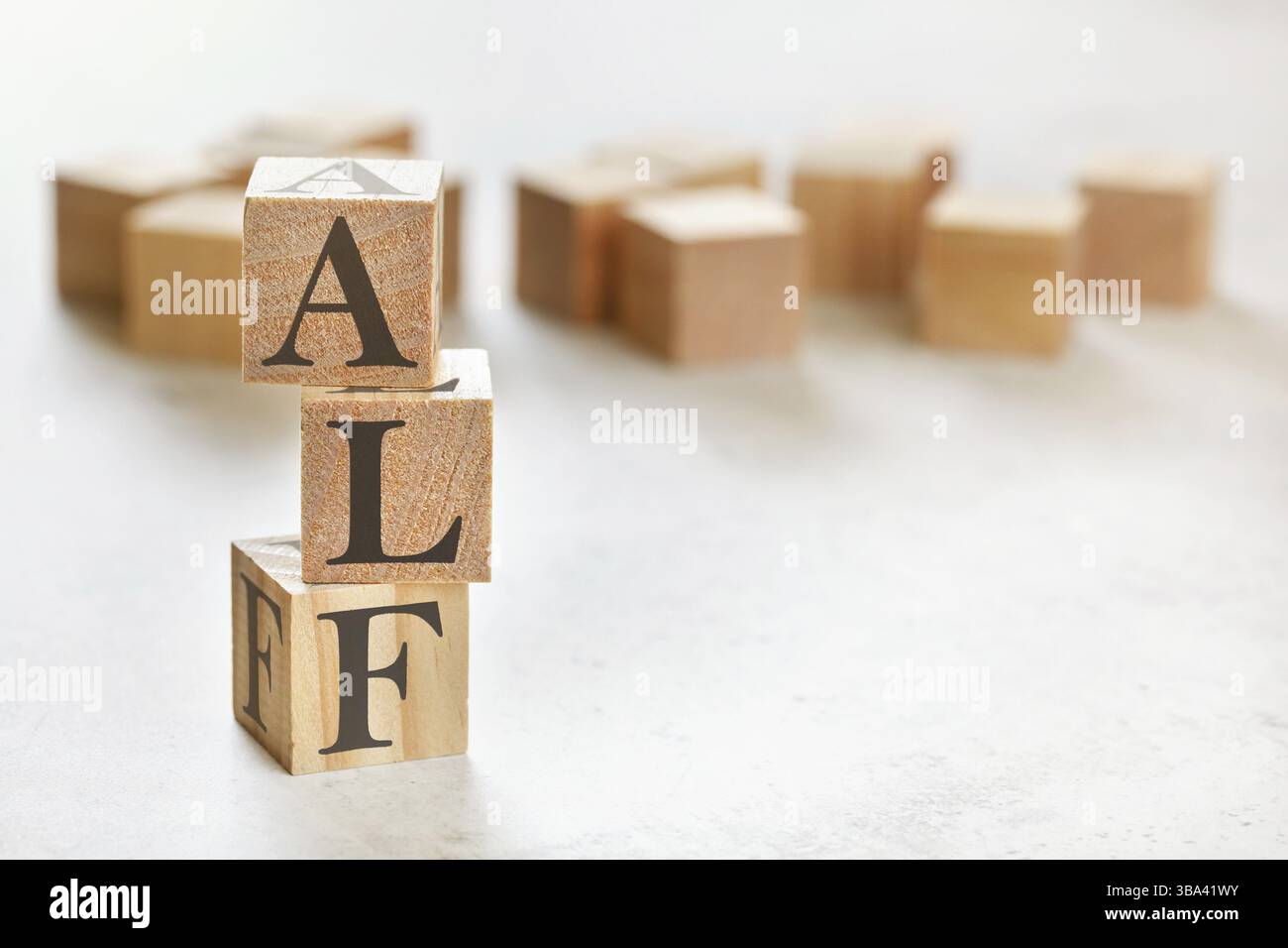 Drei Holzwürfel mit den Buchstaben ALF bedeutet immer zuerst hören, auf weißem Tisch, mehr im Hintergrund, Platz für Text in der rechten unteren Ecke, Liptovsky Hrad Stockfoto