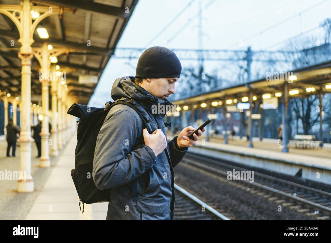 Sopot fast Urban Railway Station: Junger Mann steht und wartet auf dem Bahnsteig. Touristenfahrten mit dem Zug. Porträt Des Kaukasischen Männers In Bahn Tr Stockfoto