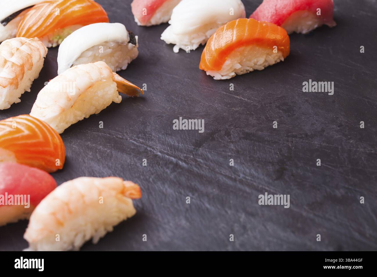 Nahaufnahme von vier Sushi mit Lachs, Thunfisch, Jakobsmuscheln und Garnelen auf schwarzem Hintergrund mit Kopierbereich Stockfoto