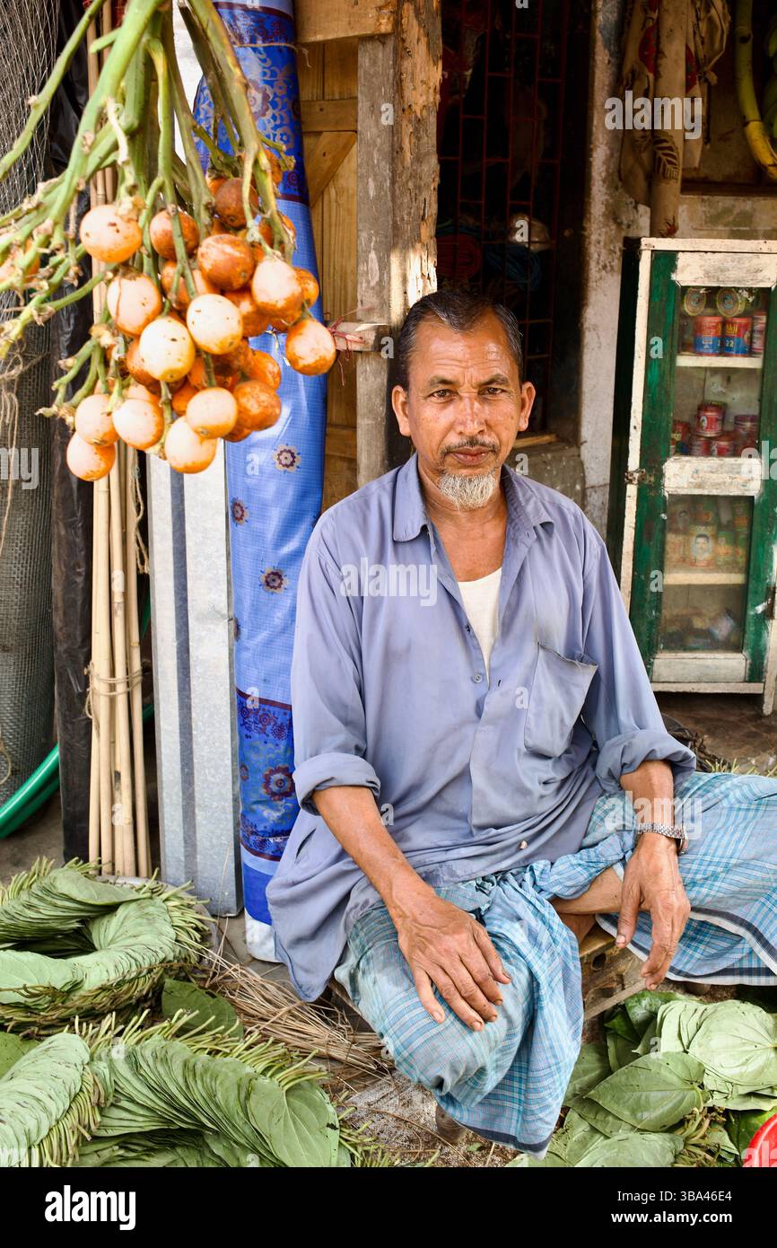 Betelblatt- und Areca-Nussverkäufer in Rangamati, Bangladesch, sitzen zwischen frischen Pfannenbündeln und Reifen Nüssen, Grundnahrungsmittel der südasiatischen Kaukultur. Stockfoto
