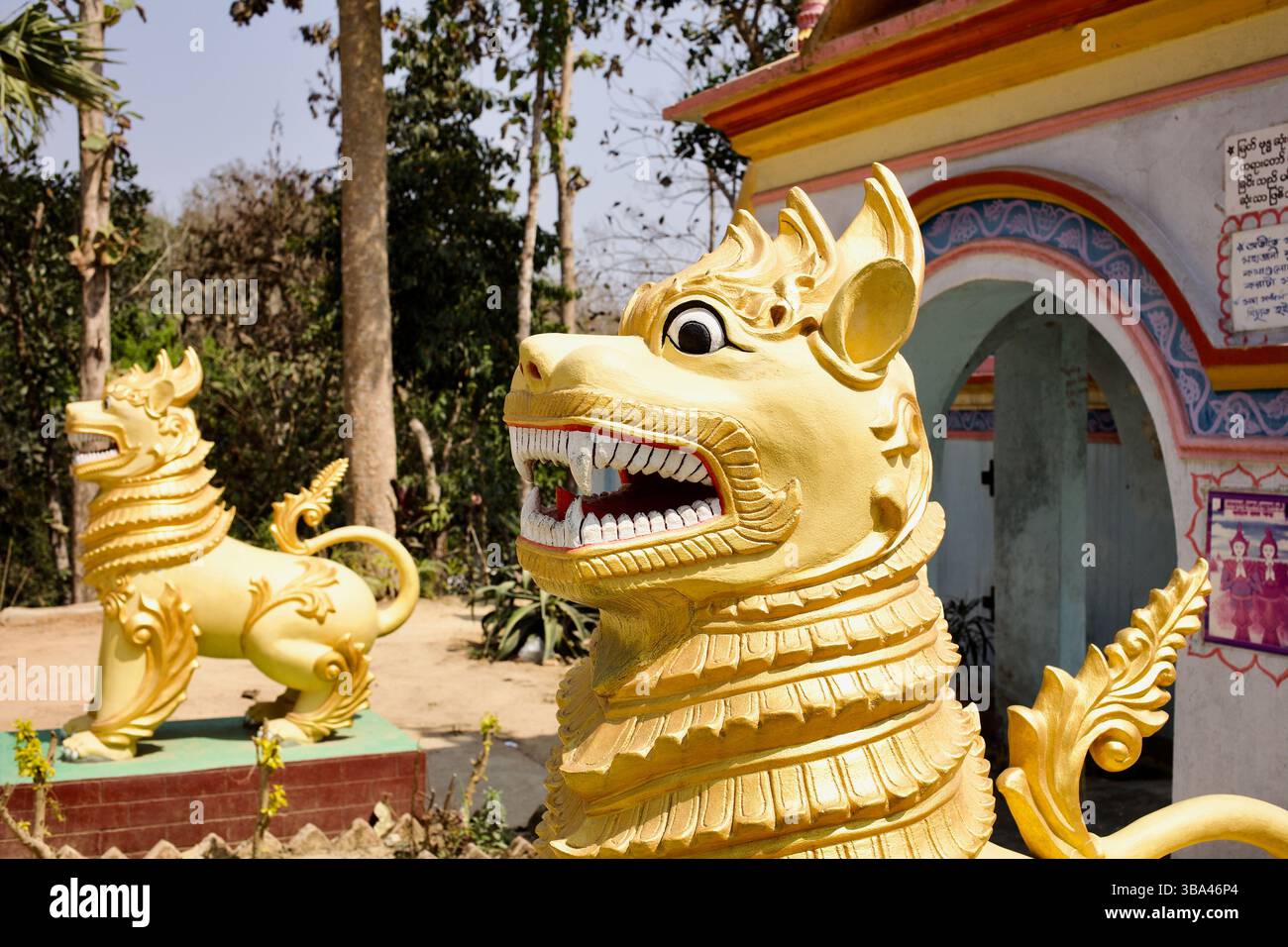 Bemalte Schutzlöwen (Chinthen) in der Chitmorom-Pagode in der Nähe von Kaptai, Bangladesch, die den Eingang zu diesem buddhistischen Schrein von Marma Theravāda bewachen. Stockfoto