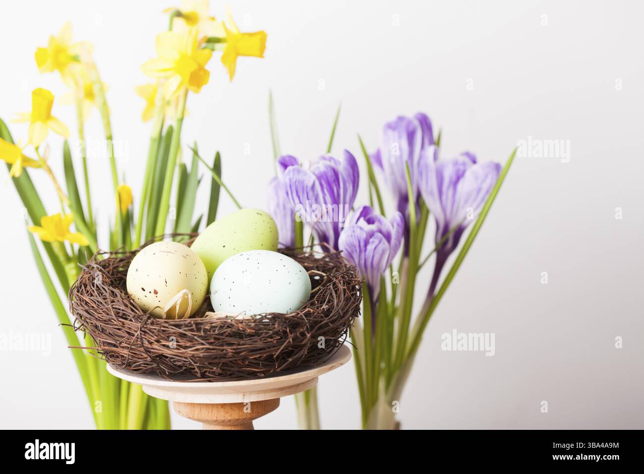 Osterdekorationen - Ei im Nest und Blumen auf dem Tisch Stockfoto