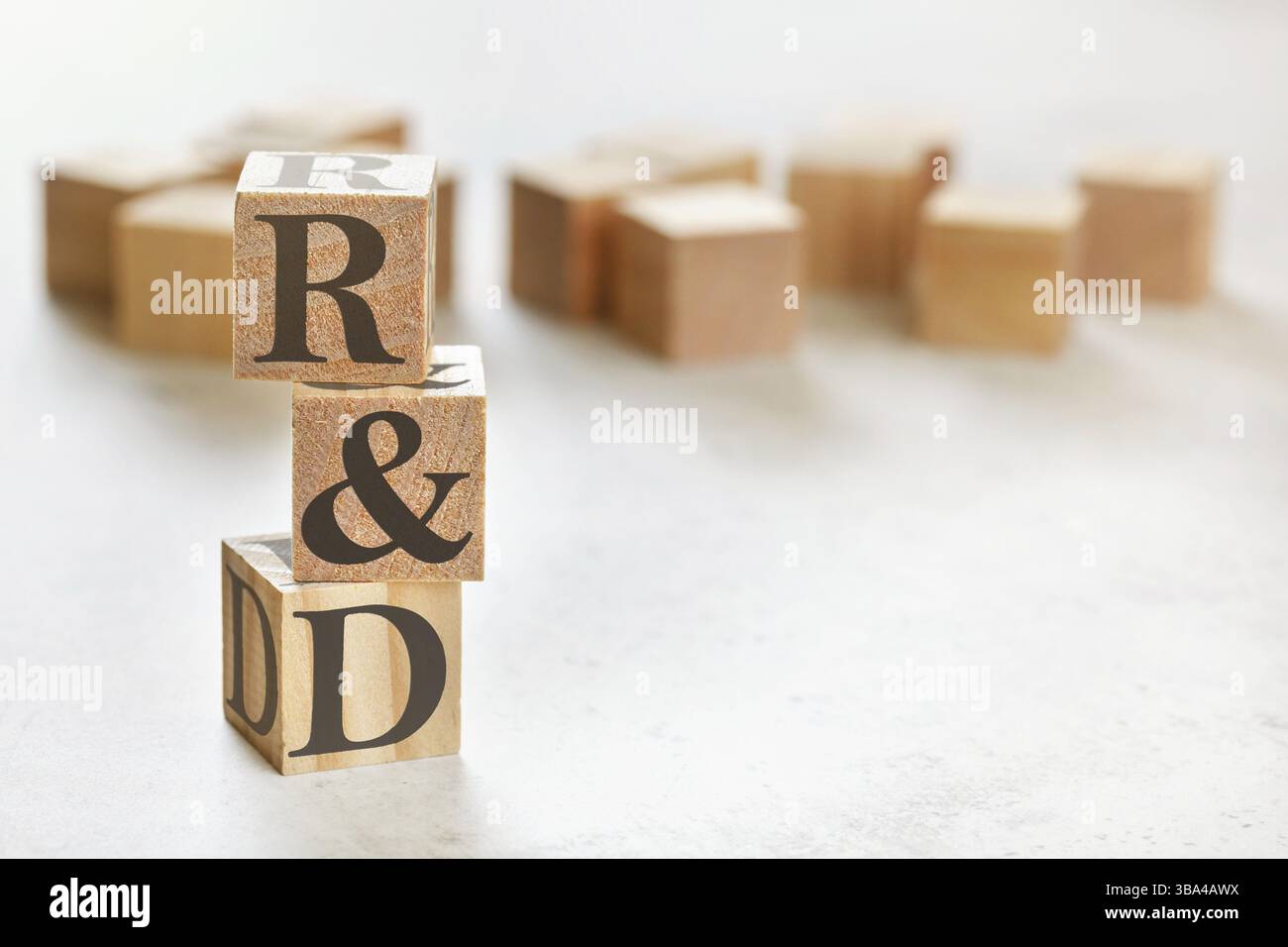 Drei Holzwürfel mit den Buchstaben F&E (bedeutet Forschung und Entwicklung), auf weißem Tisch, mehr im Hintergrund, Platz für Text in der rechten unteren Ecke, Liptovsky Stockfoto