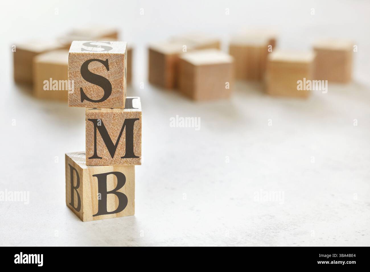 Drei Holzwürfel mit den Buchstaben SMB bedeutet kleine bis mittlere Unternehmen, auf weißem Tisch, mehr im Hintergrund, Platz für Text in der rechten unteren Ecke, Liptovsky Stockfoto