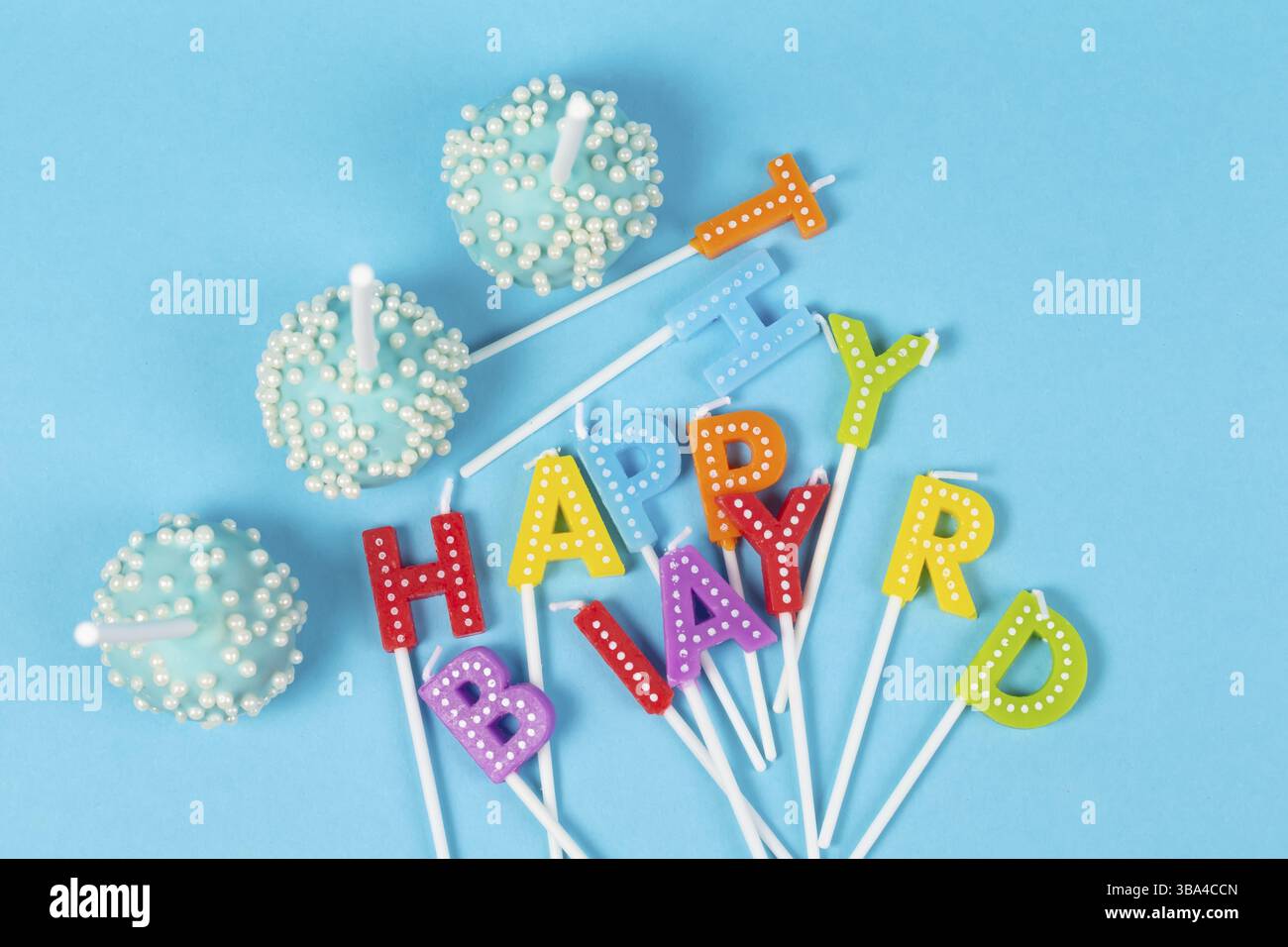 Kuchen mit regenbogenfarbenen Geburtstagskerzen mit der Aufschrift Happy Birthday Stockfoto