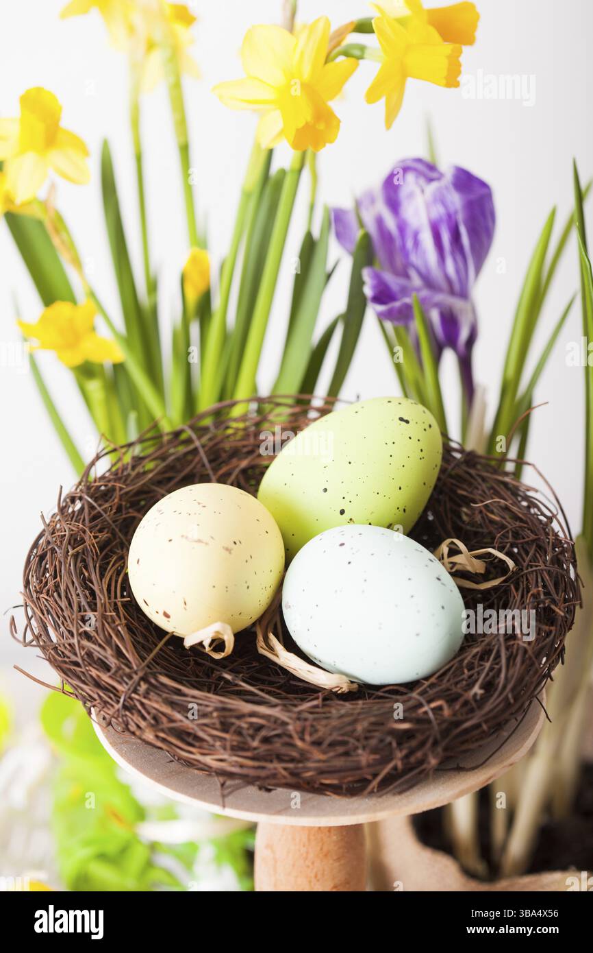 Osterdekorationen - Ei im Nest und Blumen auf dem Tisch Stockfoto