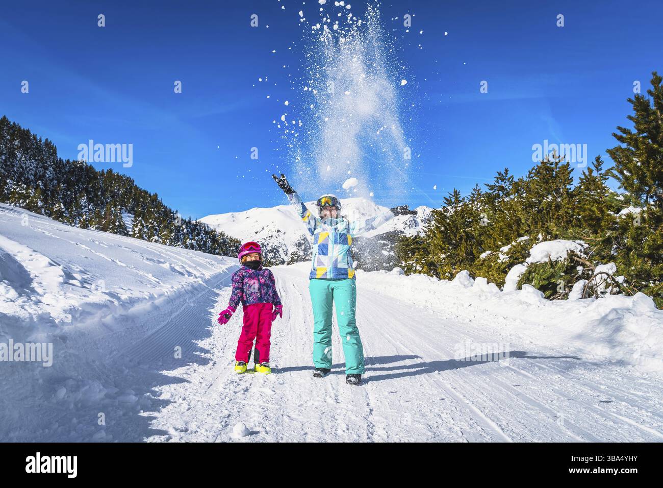 Mutter und Tochter, Familie, schmeißt Schneepulver in die Luft, Wälder und Berge im Hintergrund. Winterurlaub, El Tarter, Andorra, Pyrenäen Stockfoto