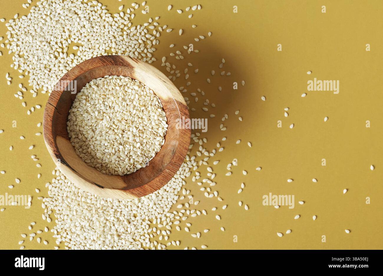 Winzige weiße Sesamsamen in einer kleinen Holzschale, auf gelbem Schreibtisch, Blick von oben, Liptovsky Mikulas, Slowakei, Europa Stockfoto