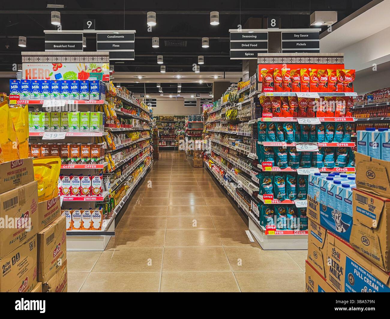 Balikpapan, Indonesien – 13. April 2025: Ein sauberer Supermarktgang mit Ultra-Milch, ABC-Sojasauce, Gewürzen und verpackten Waren unter hellem Licht Stockfoto
